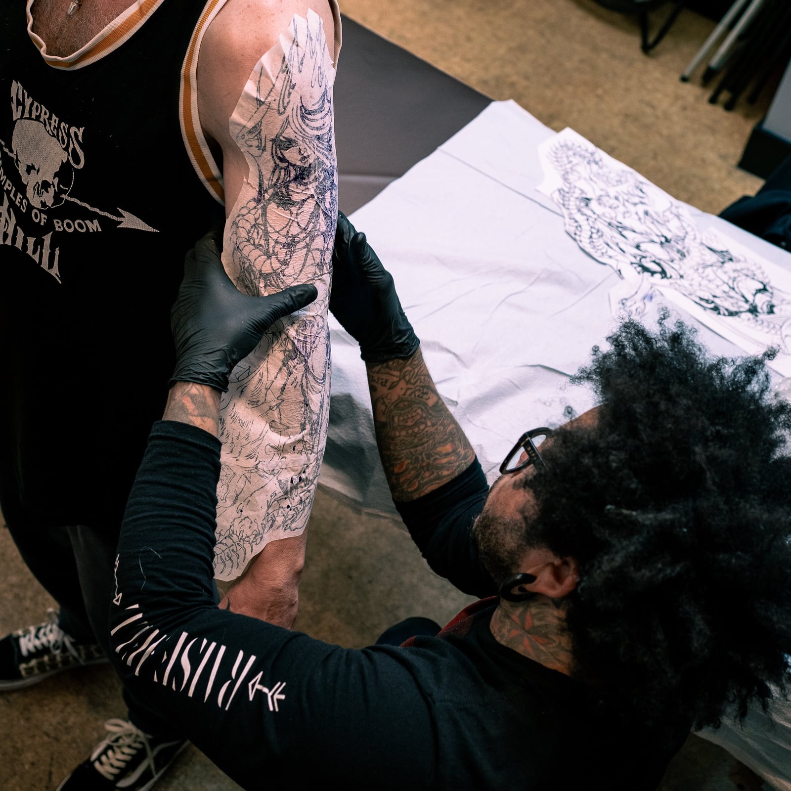 Tattoo artist applying a stencil to a client’s upper arm