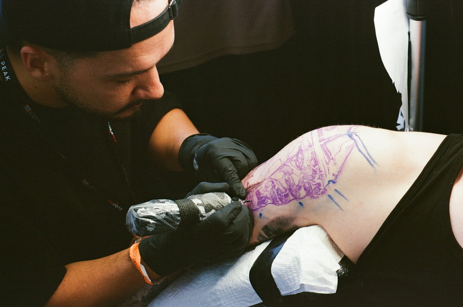 Tattoo artist working from a stencil on a client’s upper arm